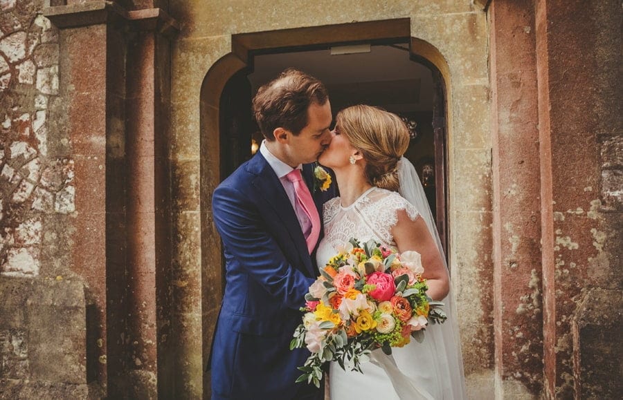The bride and groom kiss each other outside the church