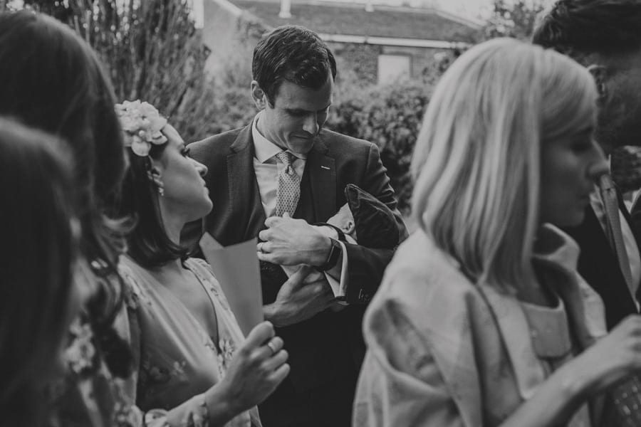 A wedding guest holds his baby boy in his arms outside the Church