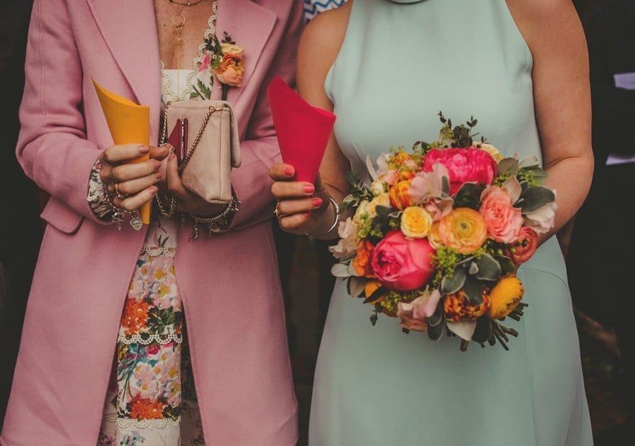 Two ladies holding confetti wait outside the church