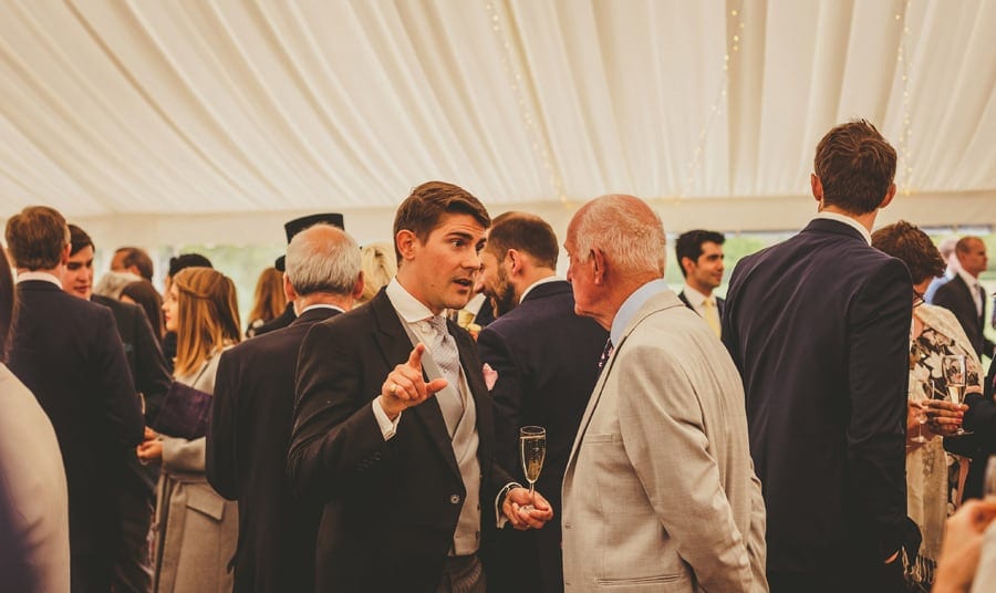 A wedding guest chats with a friend in the marquee