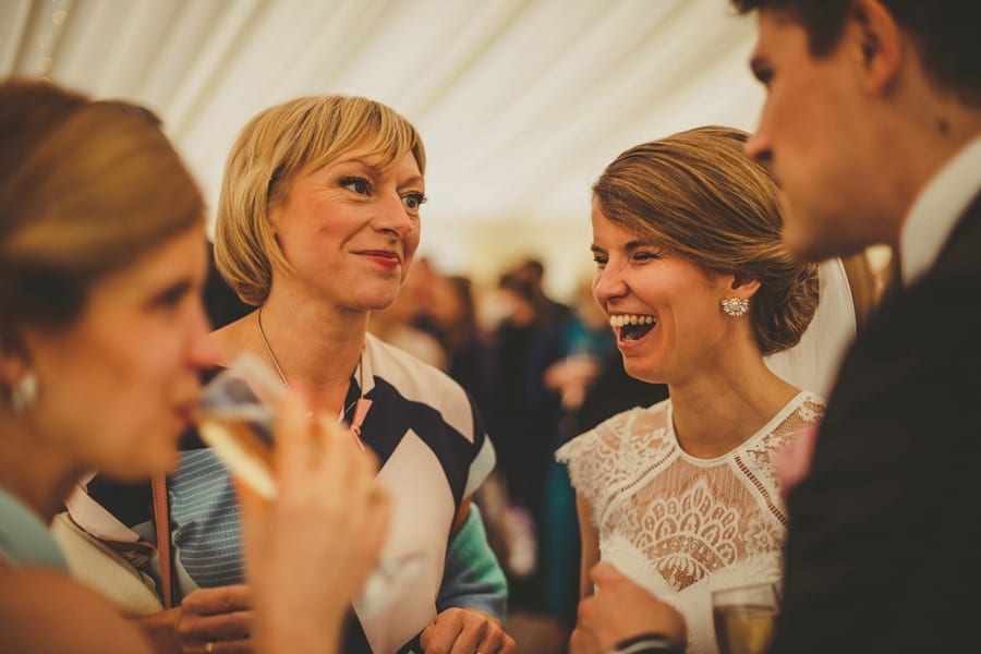 The bride laughs at a joke told by a wedding guest in the marquee