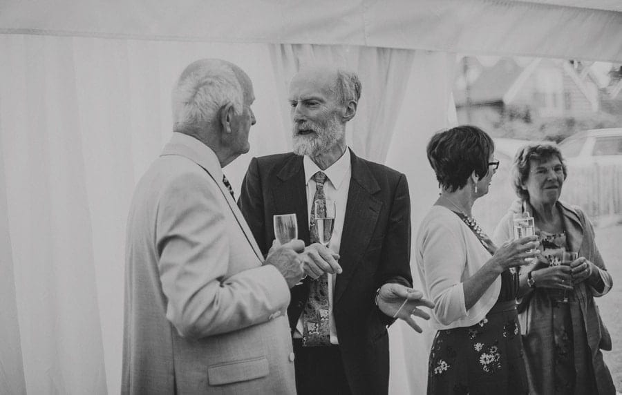 A wedding guest talks to a family member as they hold champagne flutes