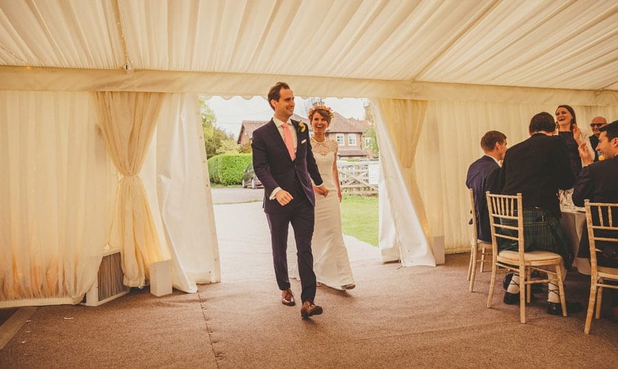 The bride and groom enter the marquee holding hands