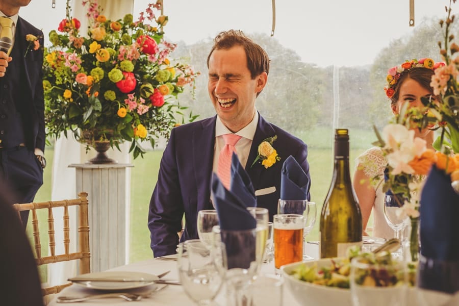 The groom sits at the wedding table and laughs
