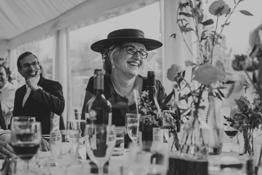 A wedding guest laughs at a speech in the marquee