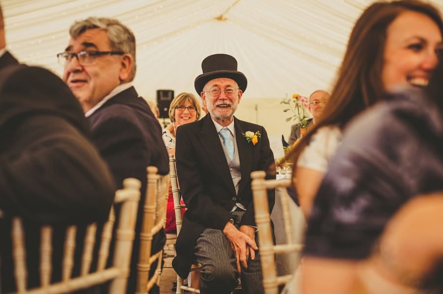 The brides father sits at a table and listens to the speeches in the marquee