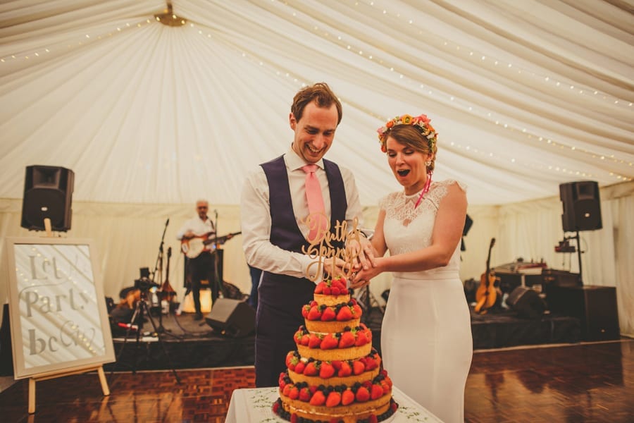 The bride and groom cut the wedding cake on the dancefloor in the marquee