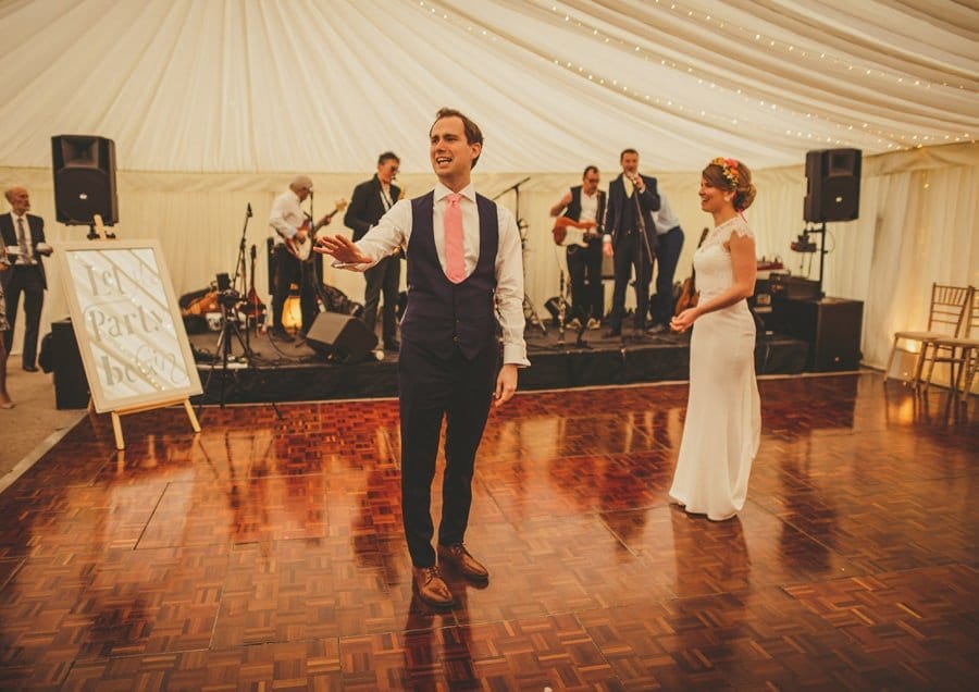 The groom talks to wedding guests on the dancefloor in the marquee