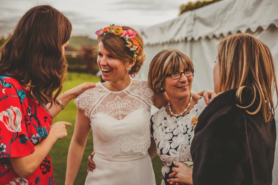The bride stands and chats to her family outside the wedding marquee in East Hampshire