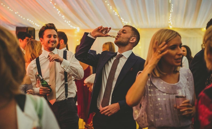A wedding guest drinks a pint of beer on the dancefloor
