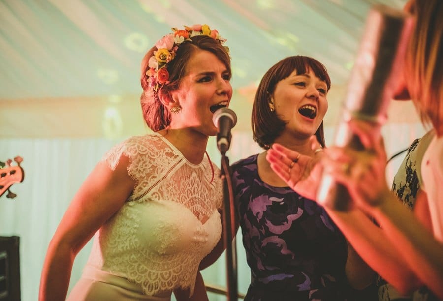 The bride sings into a microphone with her friend on stage