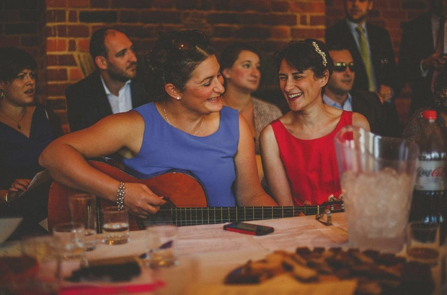A lady plays the guitar as her friend watches on in the gardens at Micklefield Hall