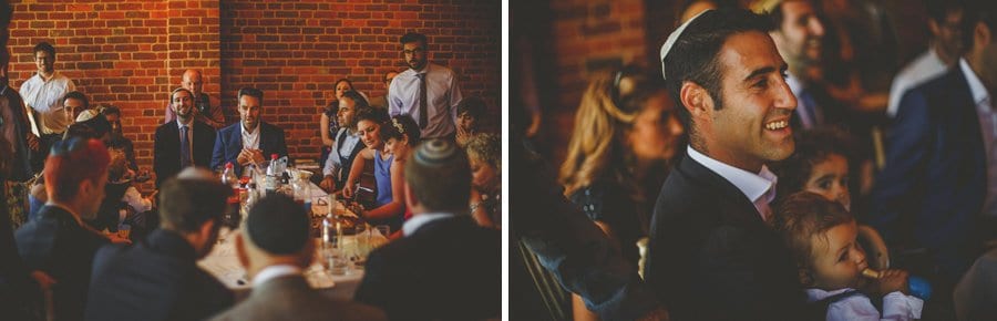 Wedding guests sit around a large wooden table in the barn at Micklefield Hall