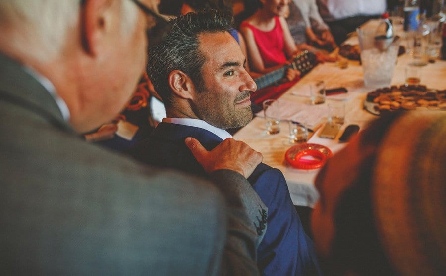 A family member places his right hand onto the shoulder of the groom in the barn at Micklefield Hall