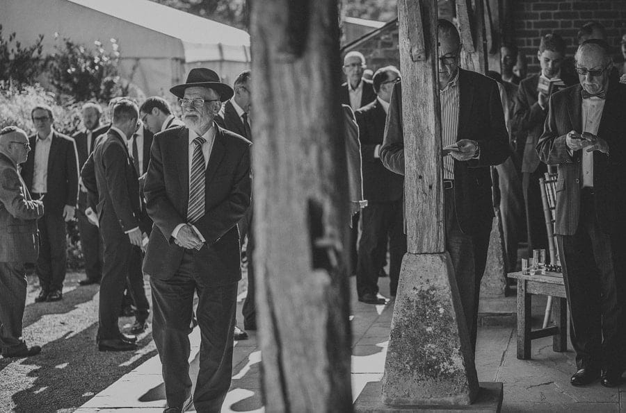Wedding guests stand and read books in the garden at Micklefield Hall