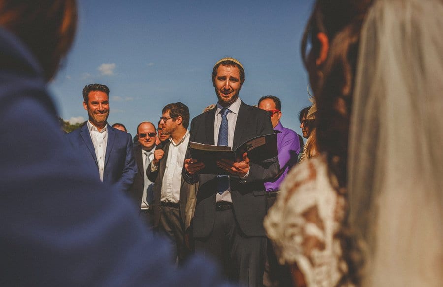 A wedding guest reads from a book at the outdoor wedding ceremony at Micklefield Hall