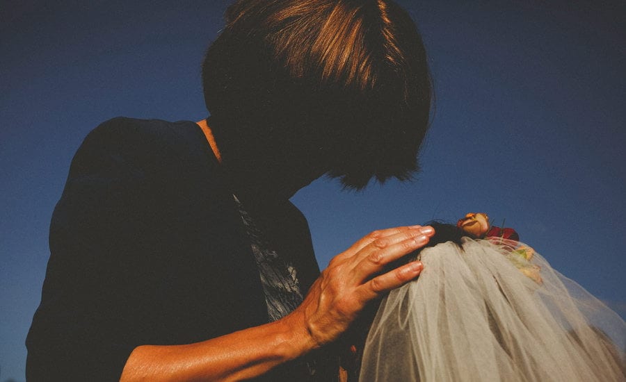 The brides mother places both hands on her daughter's head at the outdoor wedding ceremony at Micklefield Hall