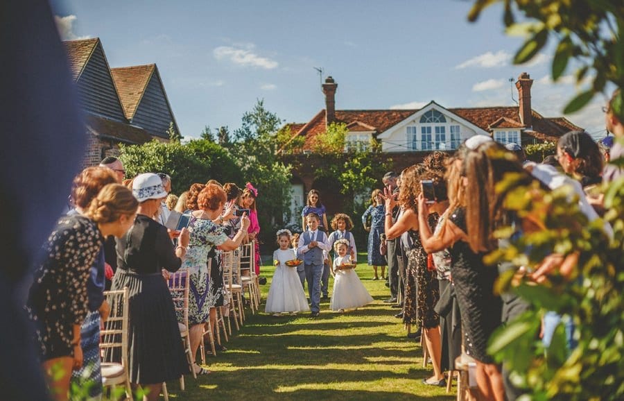The flower girls and paige boy walk up the aisle for the outdoor wedding ceremony at Micklefield Hall