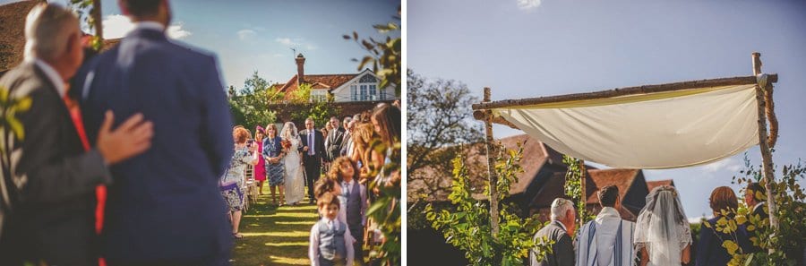 The groom watches as the bride and her parents walk up the aisle for the outdoor wedding ceremony at Micklefield Hall