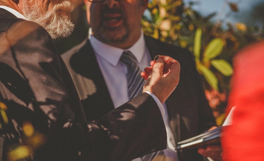 A wedding guest holds a wedding ring in his right hand during outdoor ceremony at Micklefield Hall