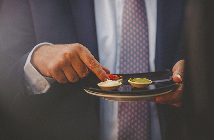 A wedding guest holds a plate with canapes on them