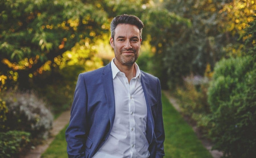 The groom poses for a photograph in the gardens at Micklefield Hall
