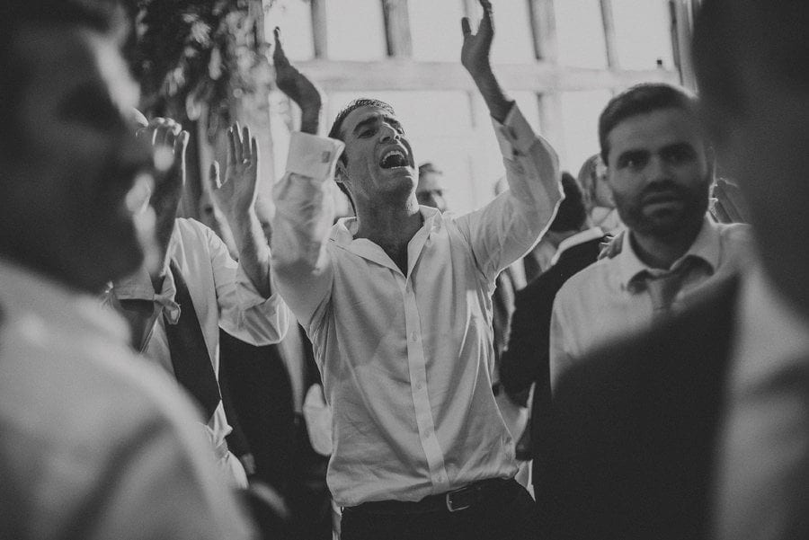 A wedding guest claps his hands in the barn on the dancefloor