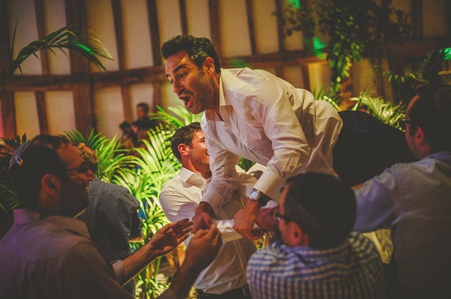 The groom's friends lift the groom over their shoulders on the dancefloor