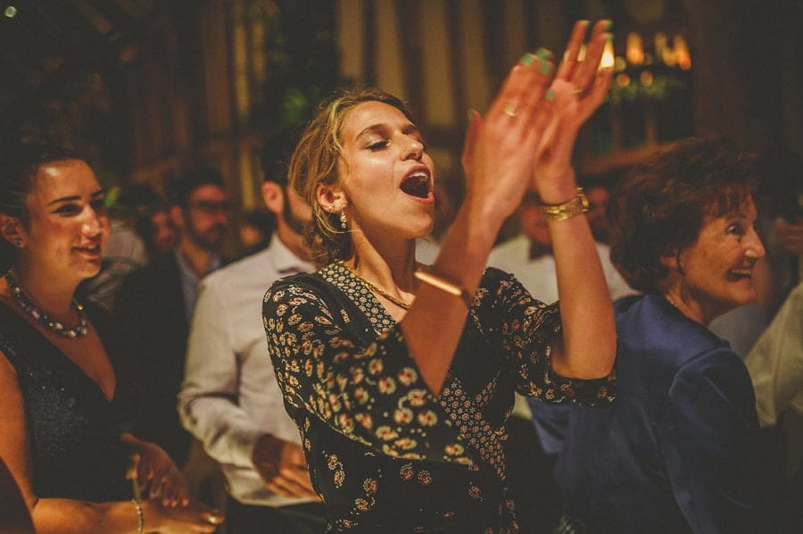 The bride's sister claps her hands on the dancefloor in the barn at Micklefield Hall