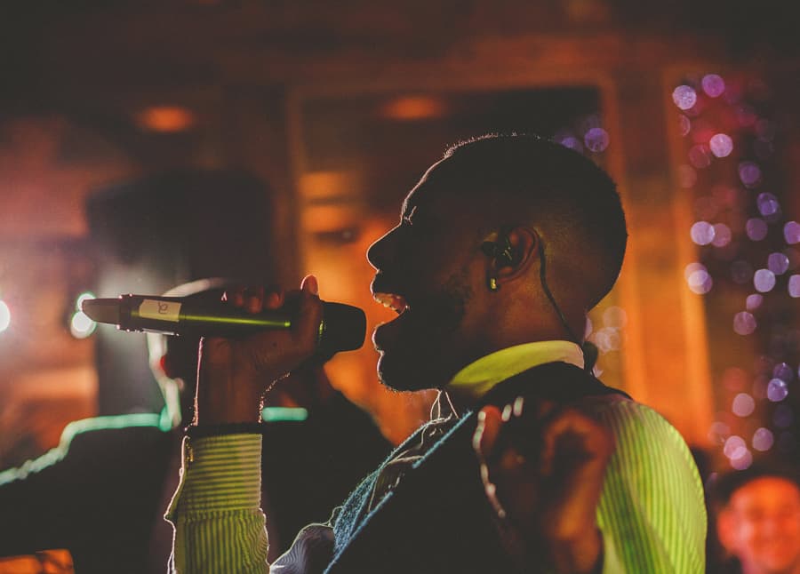 The wedding band singer performs a song on the stage in the barn at Micklefield Hall