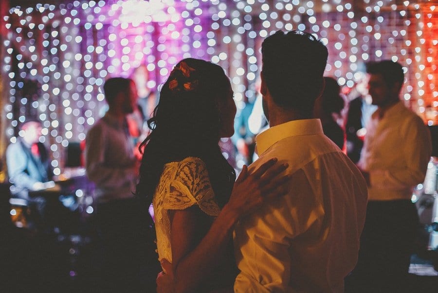 The bride and groom watch their friends and family dance together on the dancefloor in the barn at Micklefield Hall
