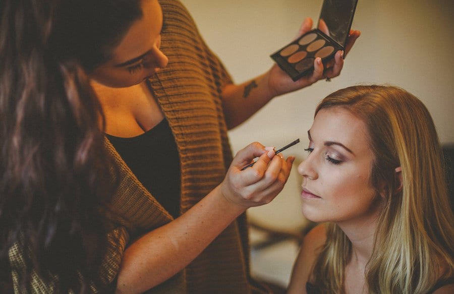 The make up artist applies makeup to a bridesmaids face