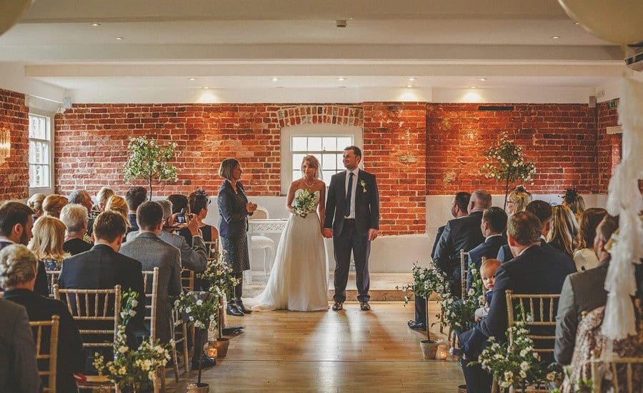The bride and groom stand and listen to the registrar during the wedding ceremony at Sopley Mill