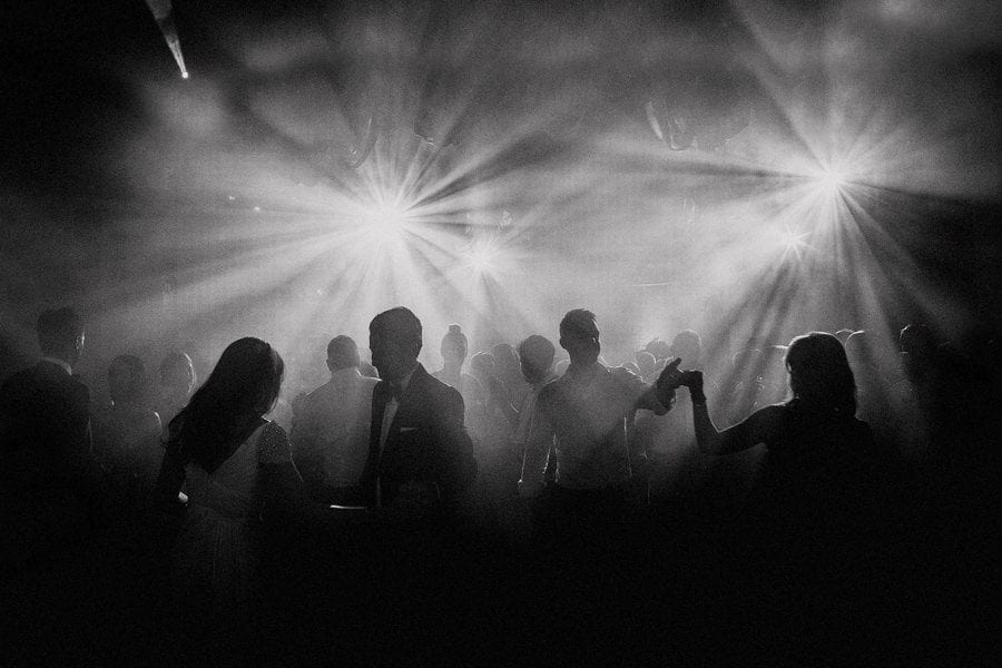 The bride and groom dance with the wedding party on the dancefloor of a big hall