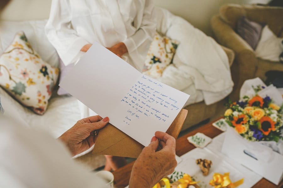 The bride's mother reads a card that was given to her by her daughter in the front room of their house