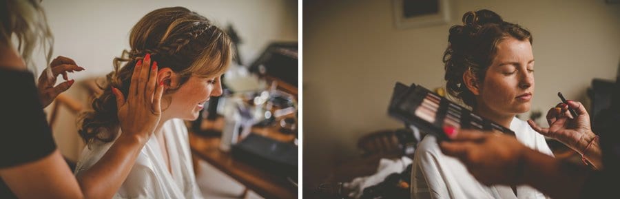 The hair stylist places a hand on the side of the head of the bride and the makeup artist applies makeup to the face of the bride