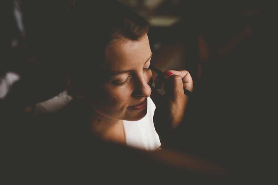 The makeup artist applies mascara to the brides left eye