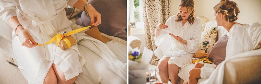 A bridesmaid opens a present given to her by the bride as they sit next to each other in the front room of the brides parent's house