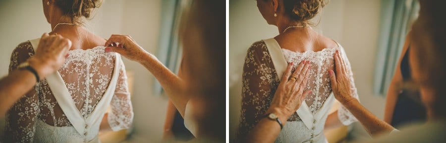 The brides mother uses her hands to straighten the back of the brides dress