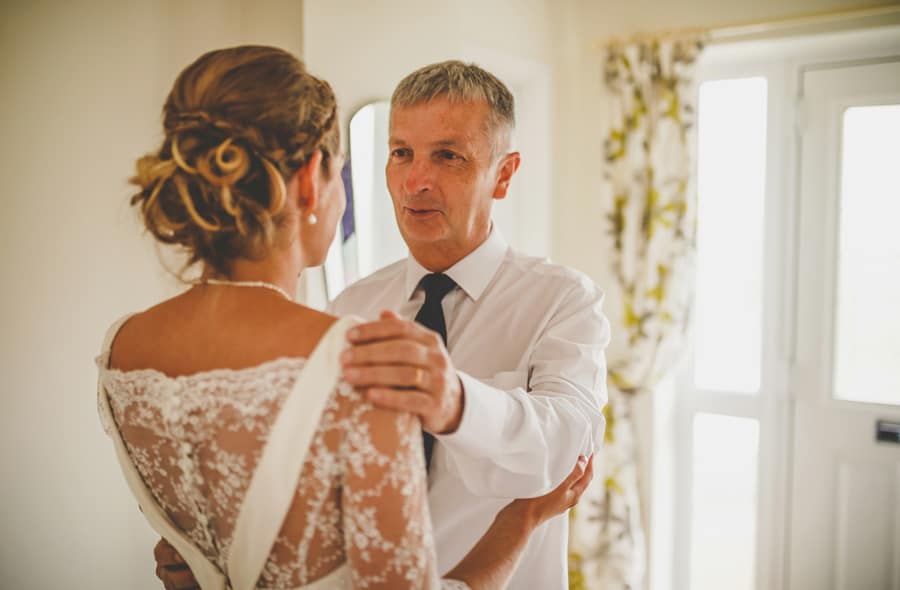 The bride's father and his daughter embrace each other at the bottom of the staircase