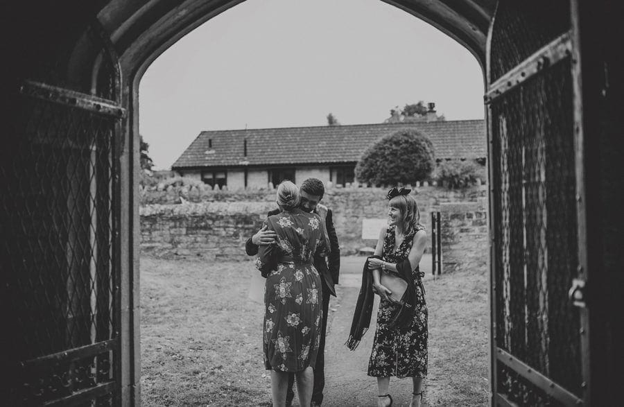 A wedding guest greets the groom's mother outside the church