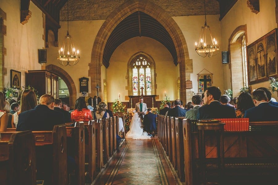 The bride and groom kneel at the alter and pray in front of the vicar during the wedding ceremony