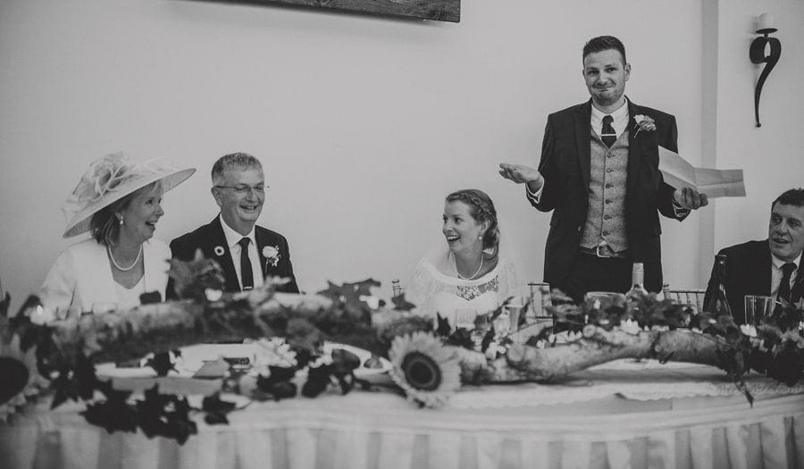 The groom delivers his speech to the wedding guests as the family are sat at the wedding table