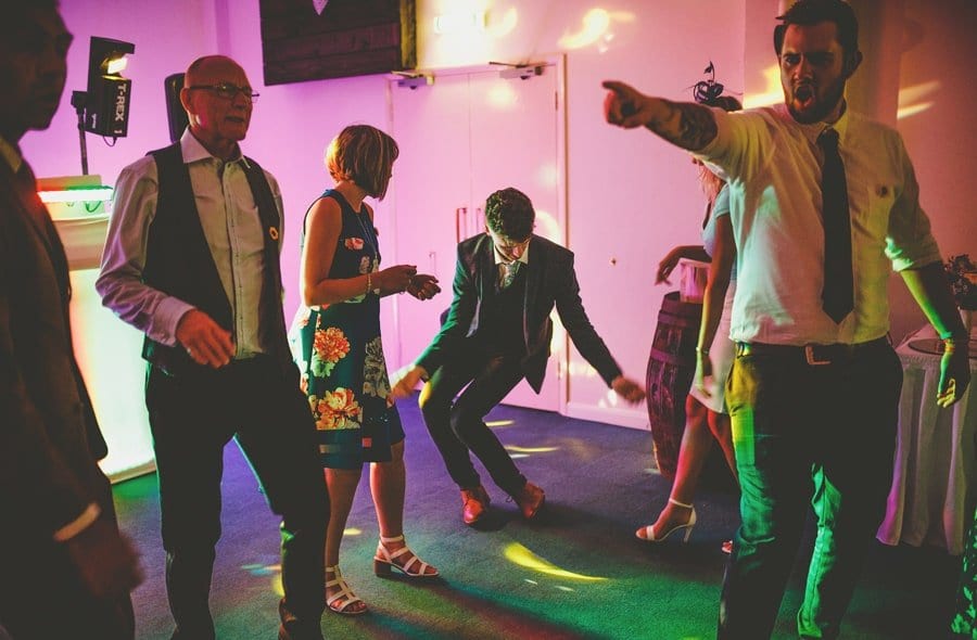A wedding guest dancing as other wedding guests stand and watch him at Yarlington barn