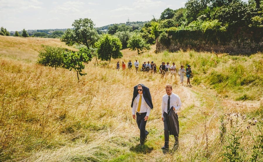 Wedding guests walking through a field towards the wedding venue