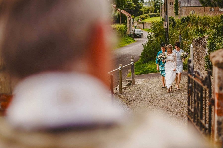 The bride and bridesmaids walk towards the vicar of the Church