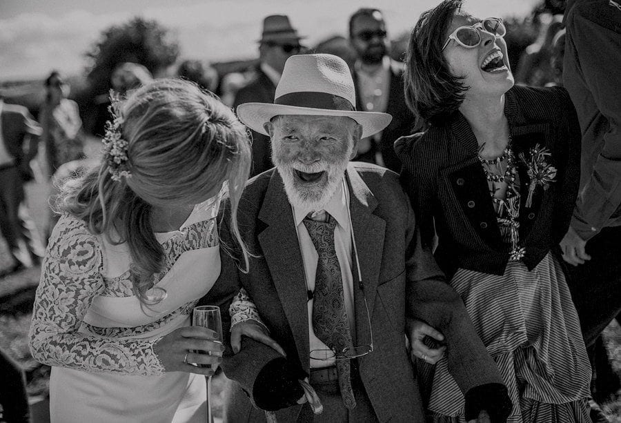 The brides grandfather laughs with the bride and her bridesmaid