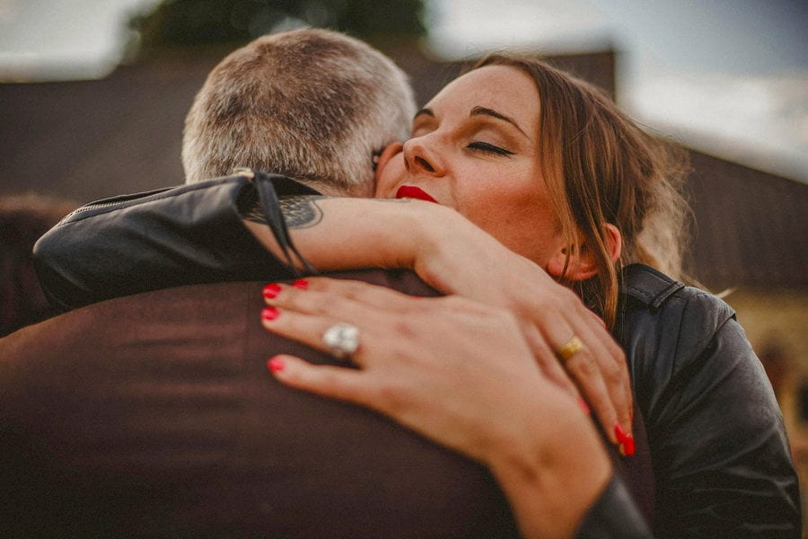 A wedding guest puts her arm around her friend and closes her eyes