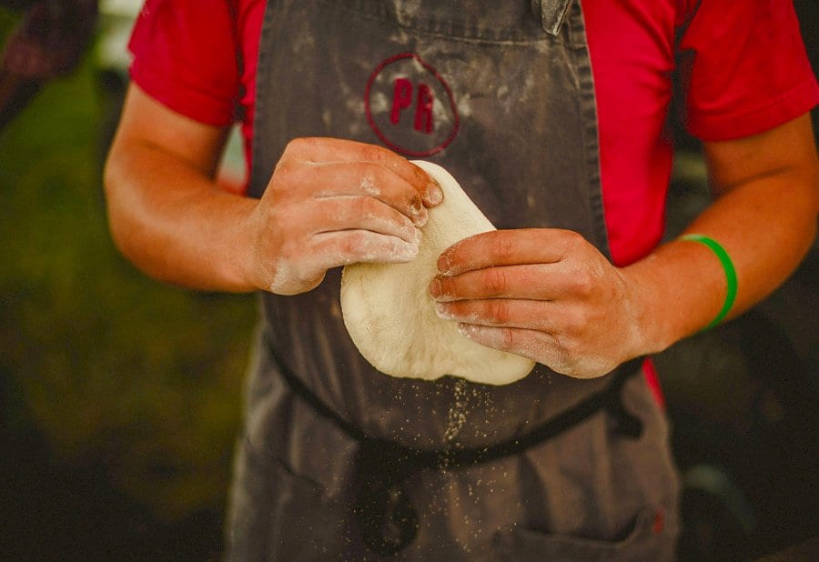 The pizza man stretches out his dough