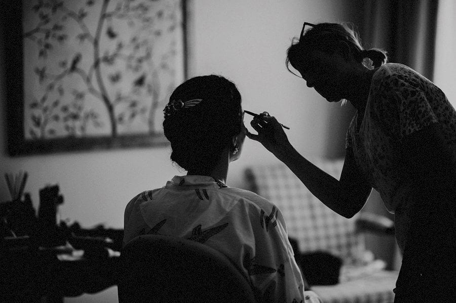 The make up artist applies make up on the brides eyebrows